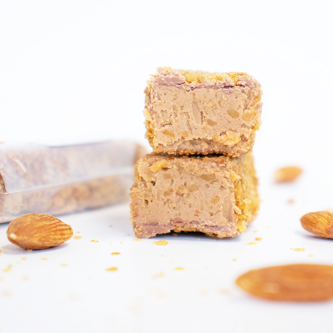 Two stacked snack bars with almonds on a white background