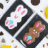 Two chocolate bunny shapes in clear packaging with Oreo cookies and pistachios on a white background.