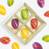 Colorful Easter egg-shaped candies in a gold tray on a white background