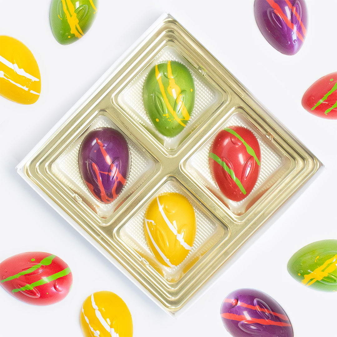 Colorful Easter egg-shaped candies in a gold tray on a white background