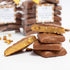 Stack of chocolate-covered peanut butter bars with a blurred background of more bars.
