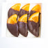 Chocolate-dipped orange slices in a clear plastic packaging on a white background