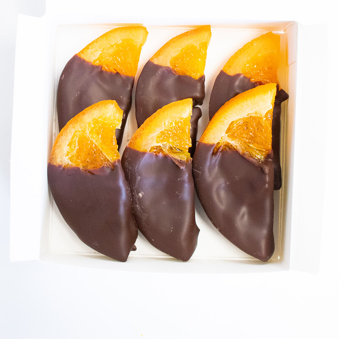 Chocolate-dipped orange slices in a clear plastic packaging on a white background