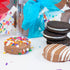 Decorative cookies with colorful sprinkles, chocolate, and a stack of Oreo cookies on a white surface.