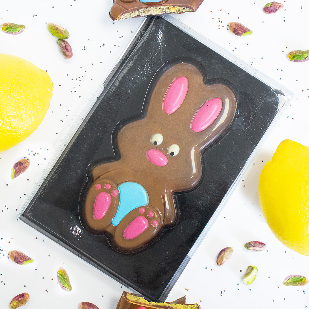 Chocolate bunny mold on a white surface with colorful candies around