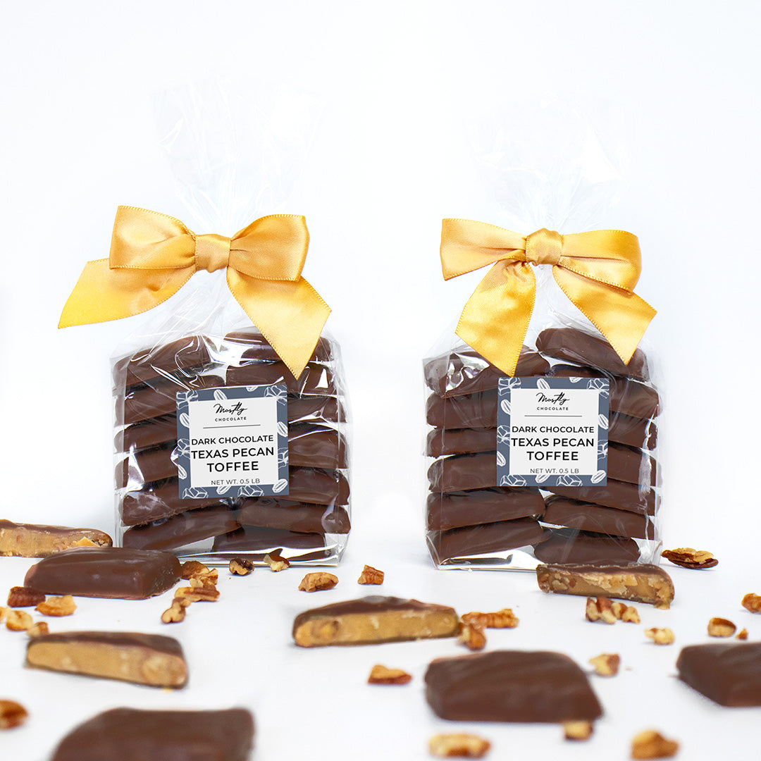 Two packages of Dark Chocolate Texas Pecan Toffee with yellow ribbons on a white background.